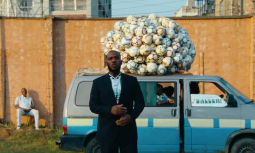 A man standing behind a truck loaded with footballs