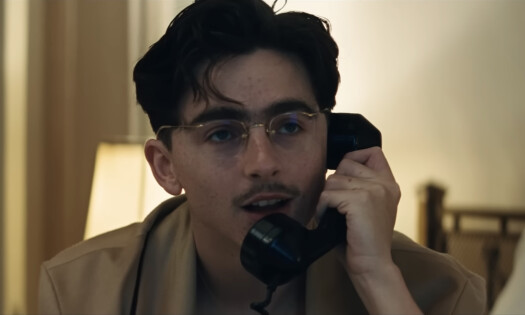 A screenshot of actor Timothée Chalamet using a landline phone in a scene from "Marty Supreme"