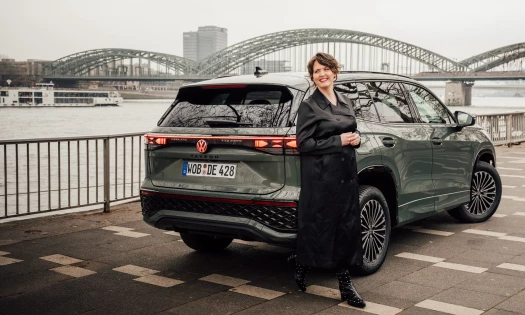 Actress Emily Cox pictured standing in front of a Volkswagen Tayron SUV