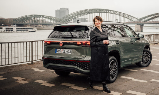 Actress Emily Cox pictured standing in front of a Volkswagen Tayron SUV