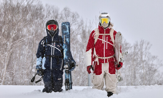 Two skiers on a snowy mountain peak rocking the new Kith x Columbia collection
