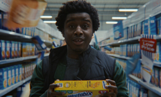 A young man holding up a box of Weetabix