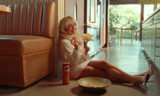 Sabrina Carpenter with a can of Pringles sat on the floor