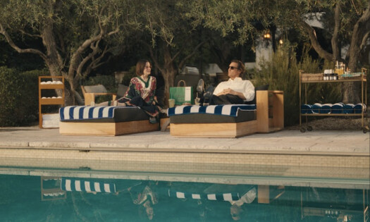 Actors Parker Posey and Matthew McConaughey pictured sitting side-by-side on chairs next to a pool