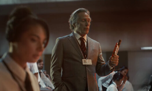 Paige DeSorbo and William Fichtner holding a Kinder Bueno chocolate in a space mission center