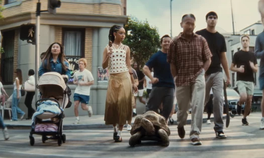 A woman enjoying her Häagen-Dazs ice cream bar while crossing the road with a tortoise