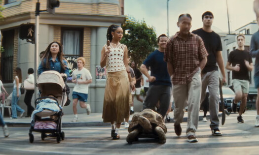 A woman enjoying her Häagen-Dazs ice cream bar while crossing the road with a tortoise