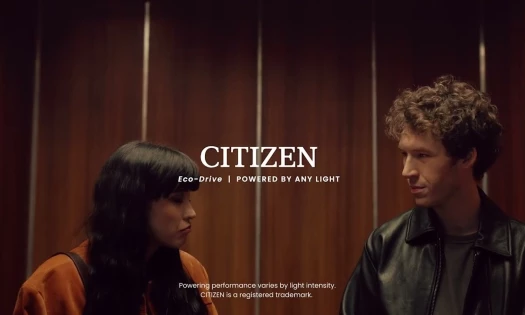 Actors Devin Druid and Annie Elliot standing side by side with the Citizen Watch logo overtop, with text reading "Eco-Drive | Powered By Any Light"