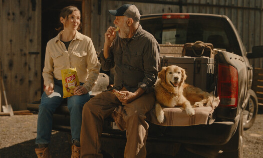 A farmer holding a bag of Lay's potato chips with a stamp that says: The Lay's Challenge from Potato to Door
