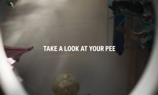 A shot shown from the perspective of inside a toilet, showing the text "Take a look at your pee"