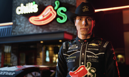 A racer donning a Chili's race jacket in front of the restaurant