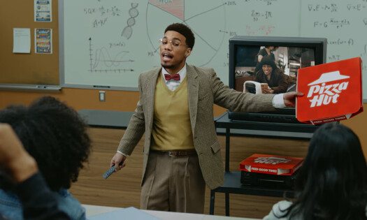 Anderson .Paak teaching students about pizza parties with a PIzza Hut box in his hand