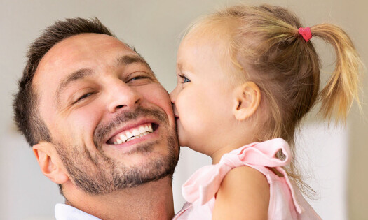 A father and young daughter pictured, with the daughter kissing the dad's cheek