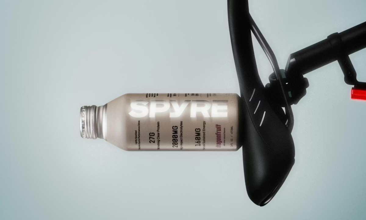 Close-up of a dragonfruit-flavored SPYRE bottle resting on a black bicycle seat