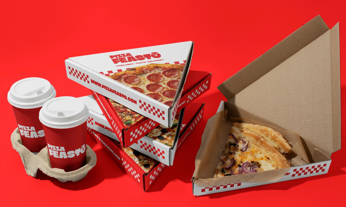 A stack of triangular white and red pizza boxes next to two red coffee-style cups