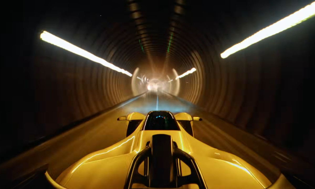 Point-of-view shot from the hood of a car racing through a glowing, dark tunnel