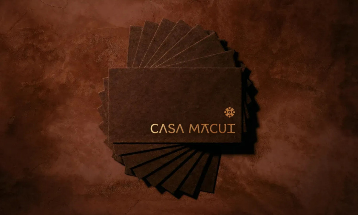 A circular fanned stack of dark, textured business cards with golden lettering