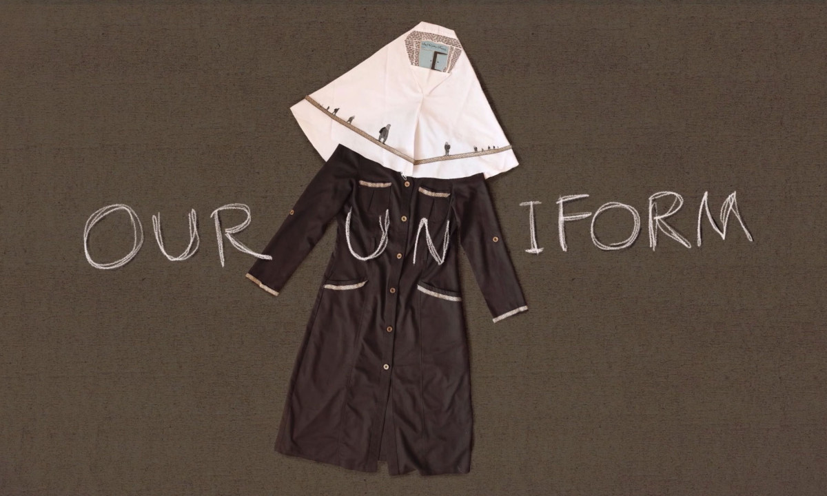 A white hijab and brown school tunic are laid flat on a textured surface with the words "OUR UNIFORM" written in a chalk-like font around them
