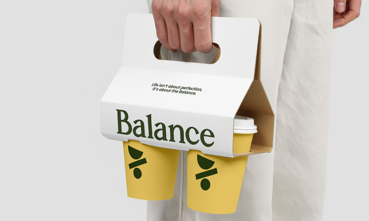 White cardboard carrier holds two yellow branded coffee cups.