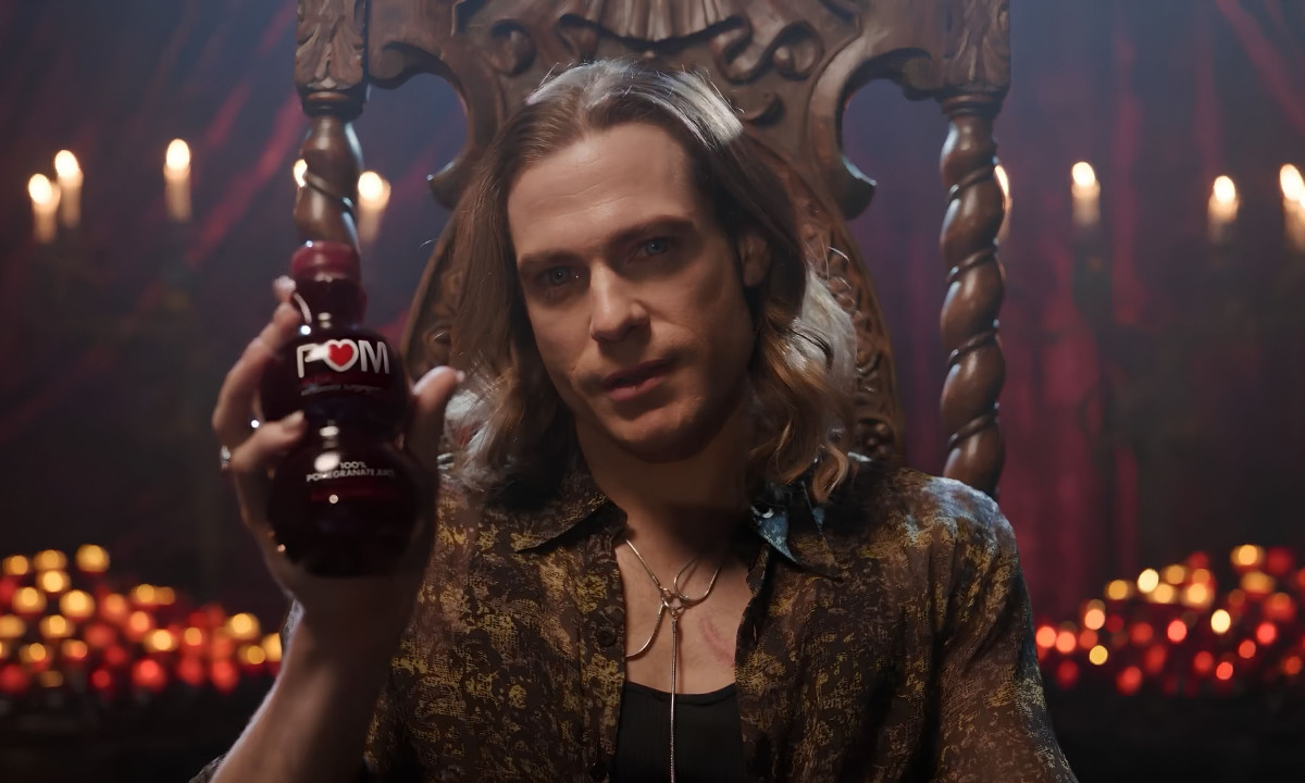 Man sits on a wooden throne holding juice.