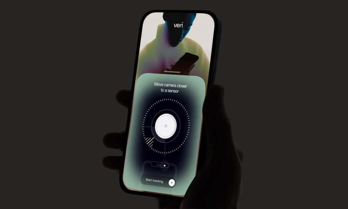 A hand holds a smartphone displaying a sensor scanning interface over a live camera feed.