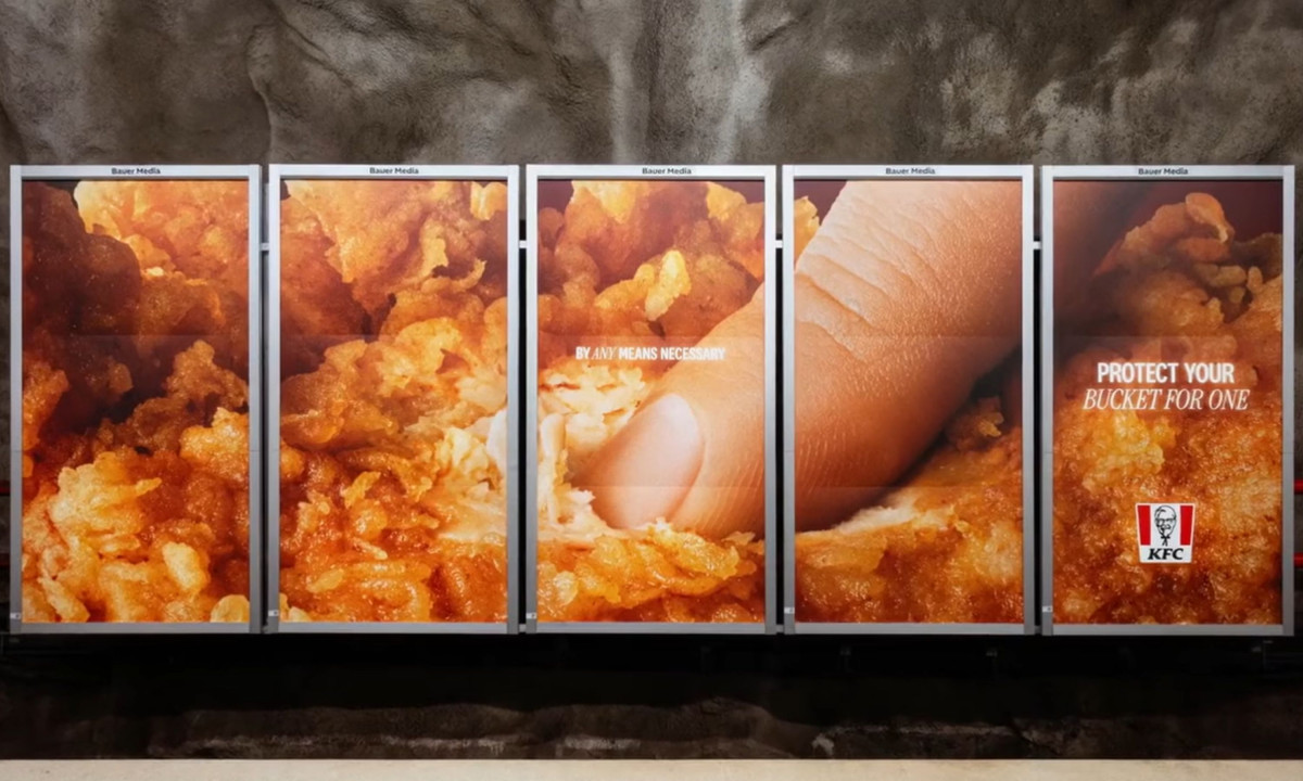 A five-panel billboard displays an extreme close-up of a finger poking into fried chicken with the text "Protect your bucket for one."