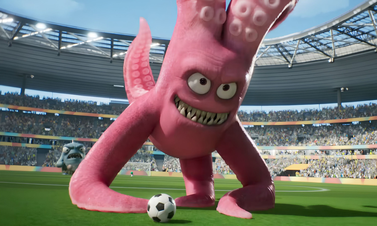 A pink monster stands over a soccer ball.