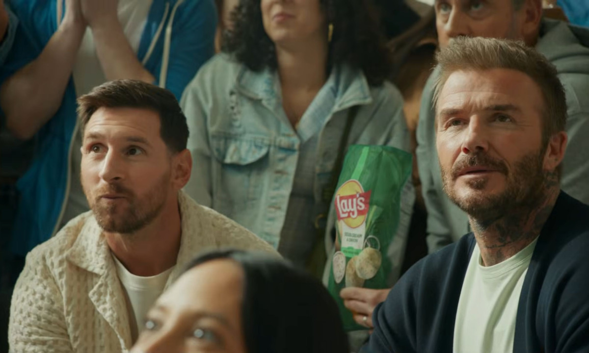 Lionel Messi and David Beckham watch a game intently.