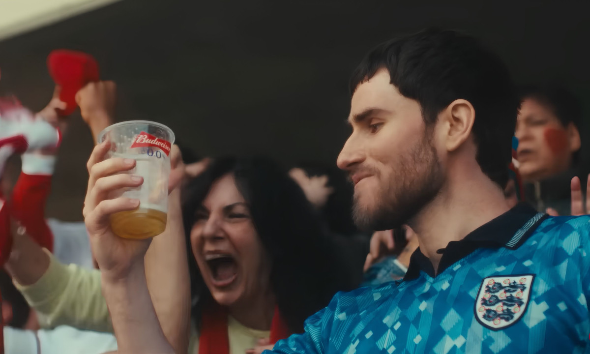 A smiling fan raises a plastic Budweiser beer cup.