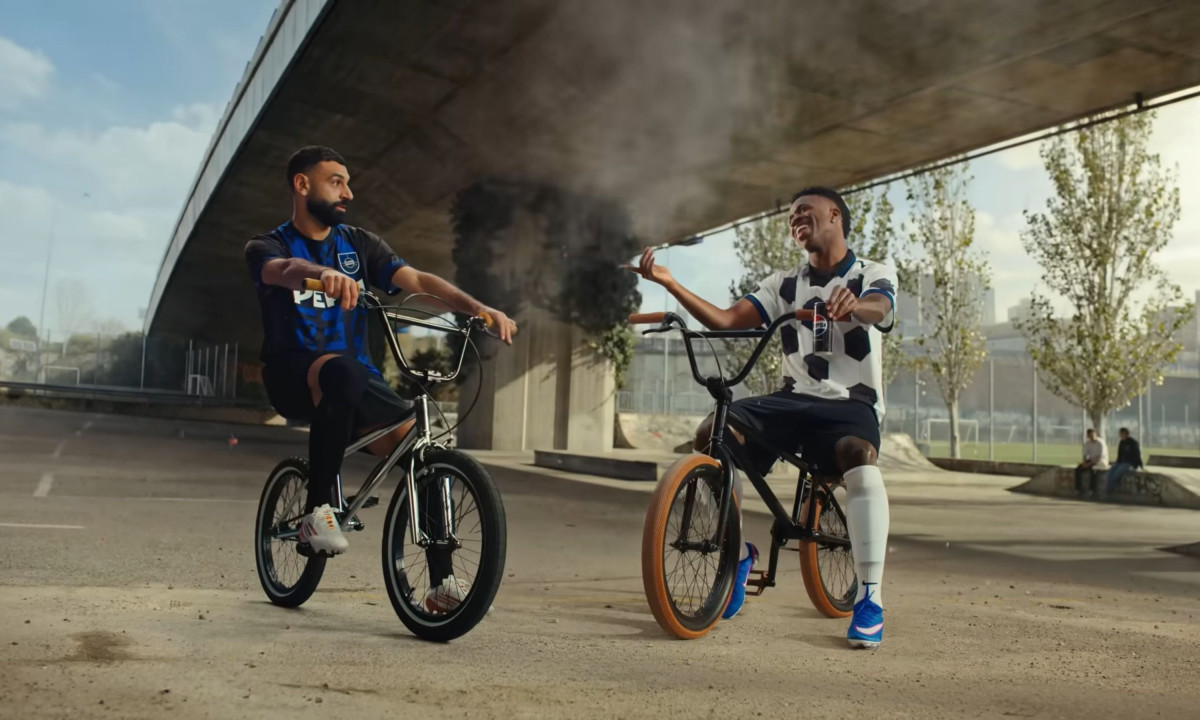 Two athletes converse while sitting on small BMX bikes.