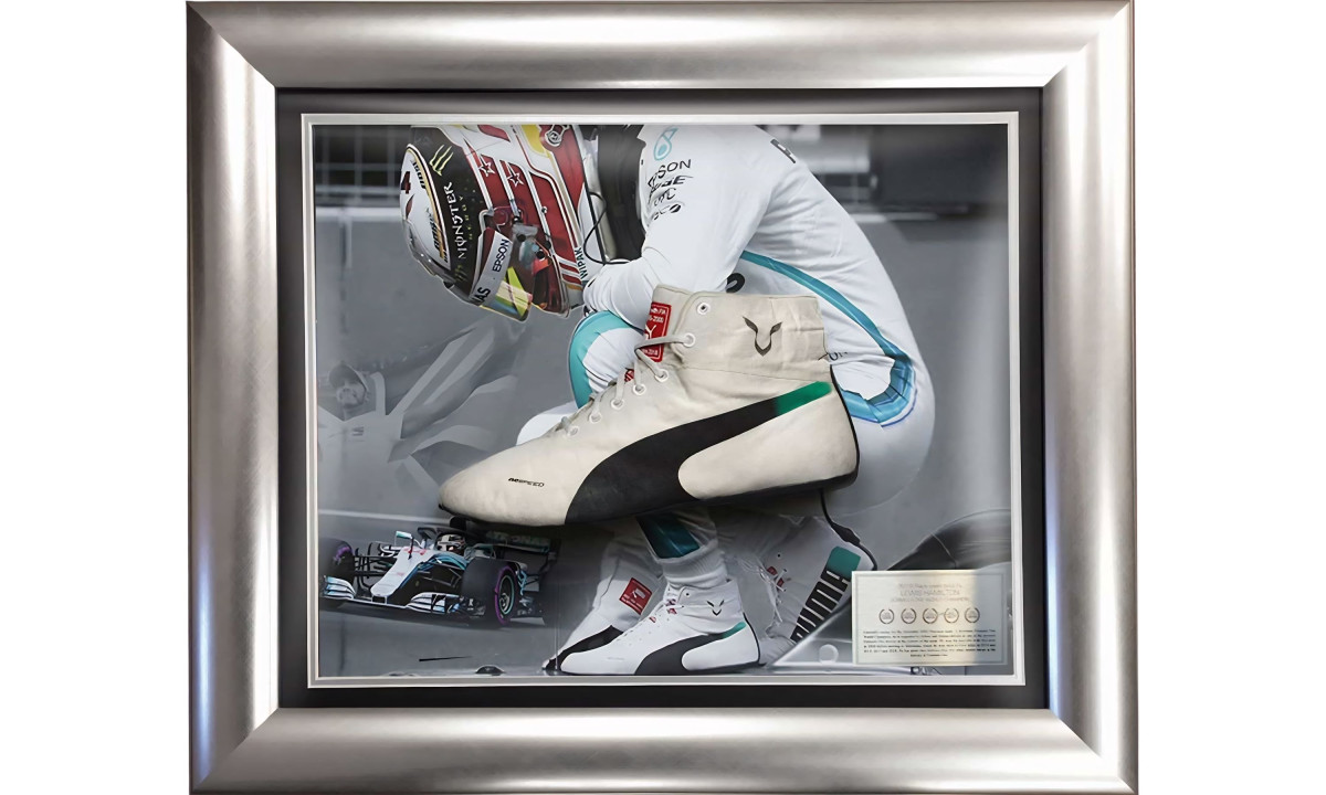 Framed display of Lewis Hamilton logo on white racing boot and driver photo.