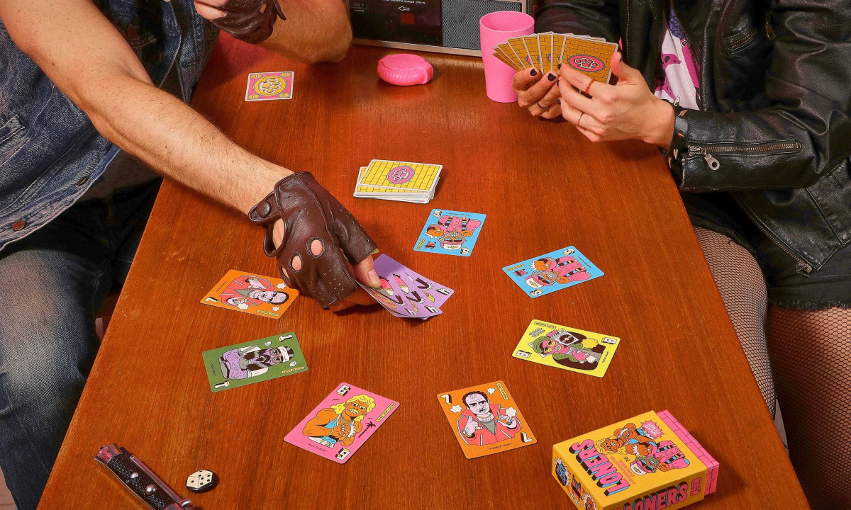 Players in leather and denim playing Loners on a wooden table.