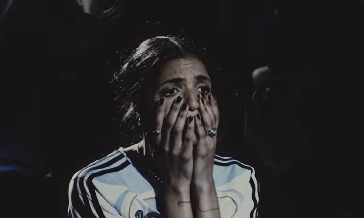 Woman in an Argentina jersey covering her face in suspense.