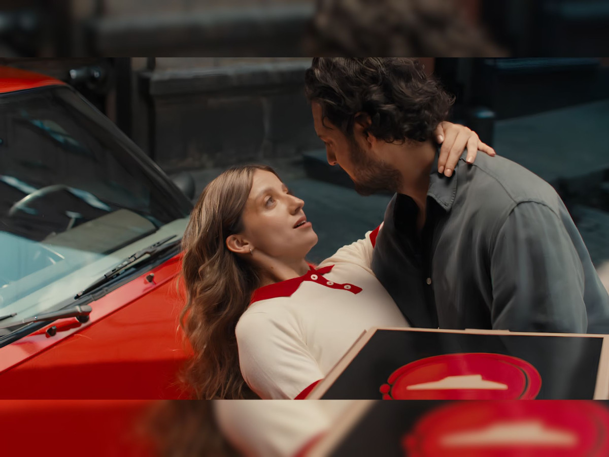 A man romantically dips a woman holding Pizza Hut boxes.