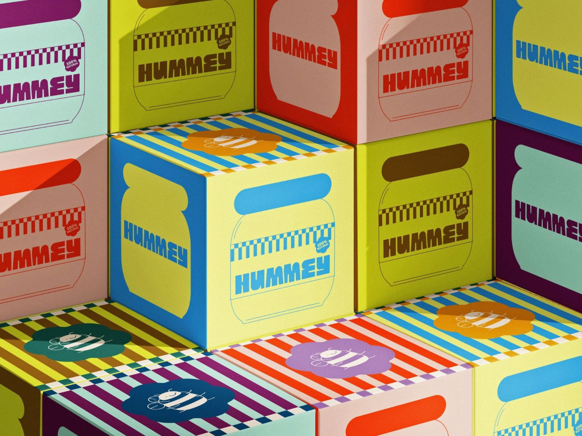 Stacked colorful boxes featuring "HUMMEY" honey jar graphics and bee logos.