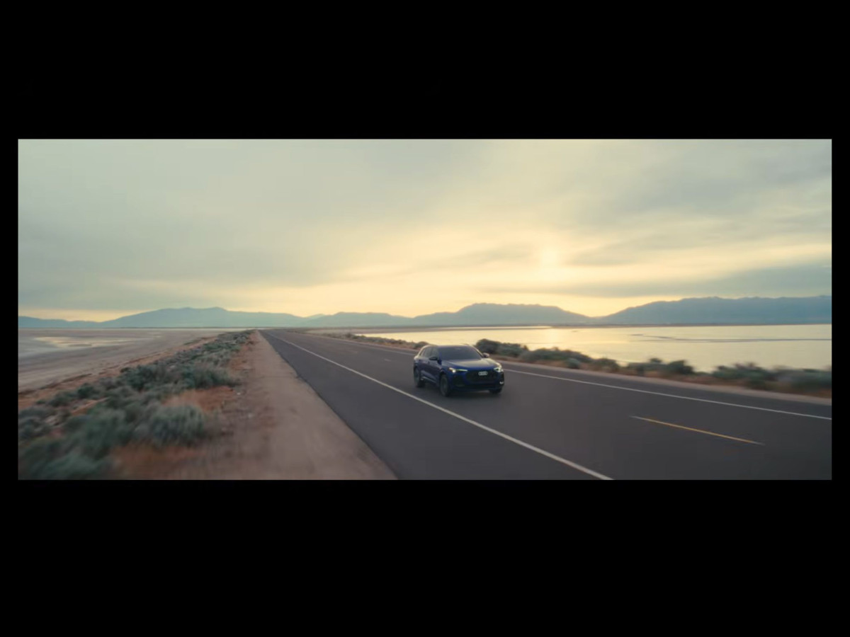 An Audi electric car driving on a coastal road at twilight.