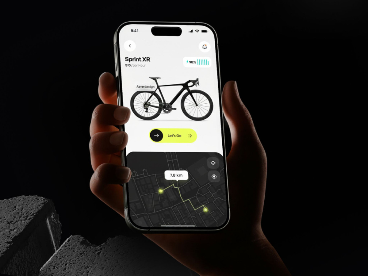 Hand holding a smartphone displaying the Rydeon app's bike selection and dark map interface.