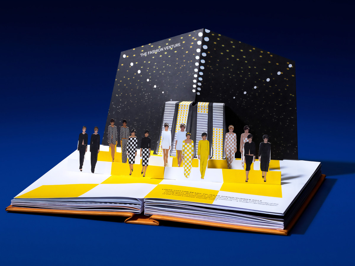 Open pop-up book displaying a 3D fashion runway scene.
