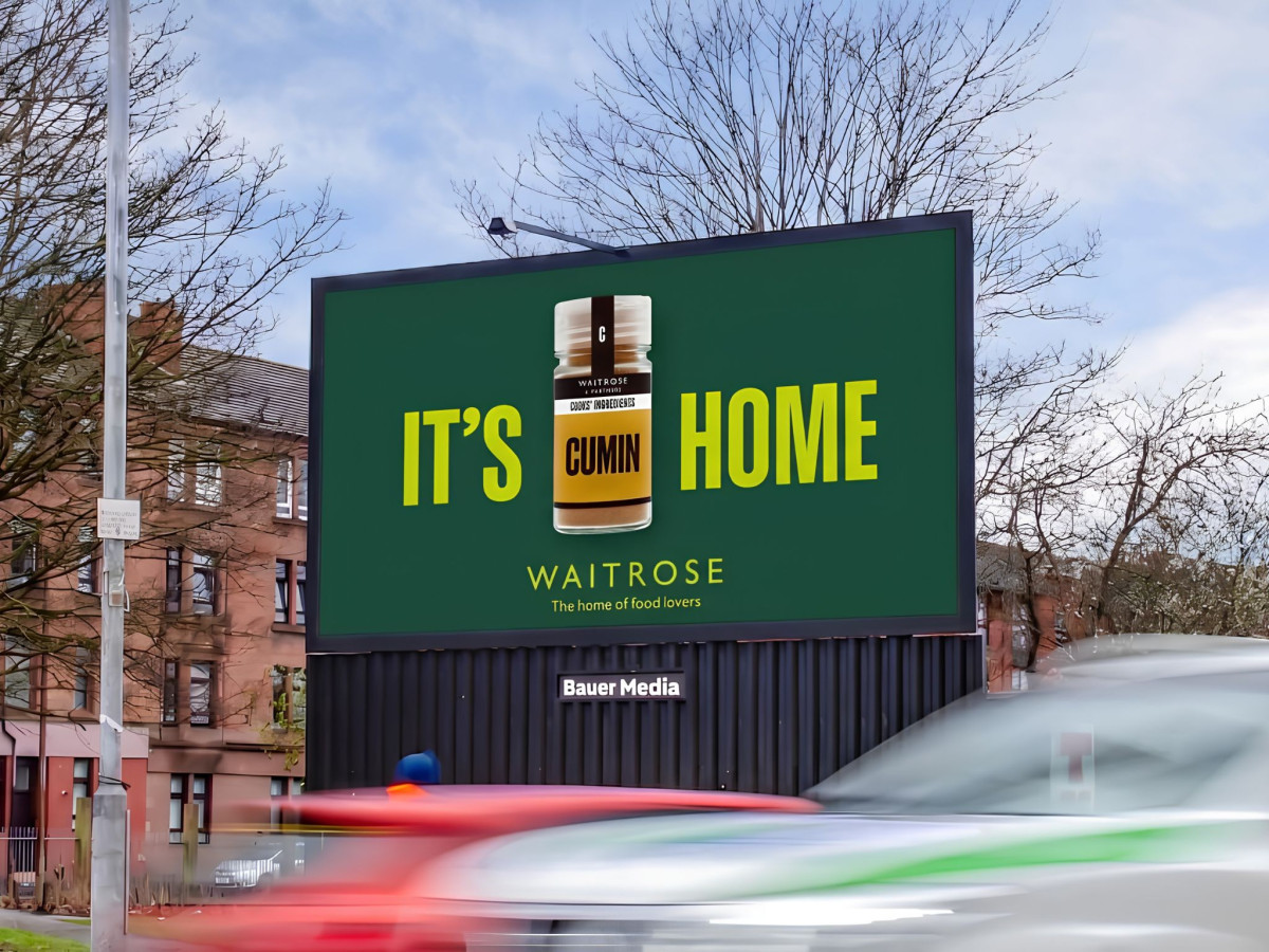 Waitrose "It's cumin home" billboard above a street.