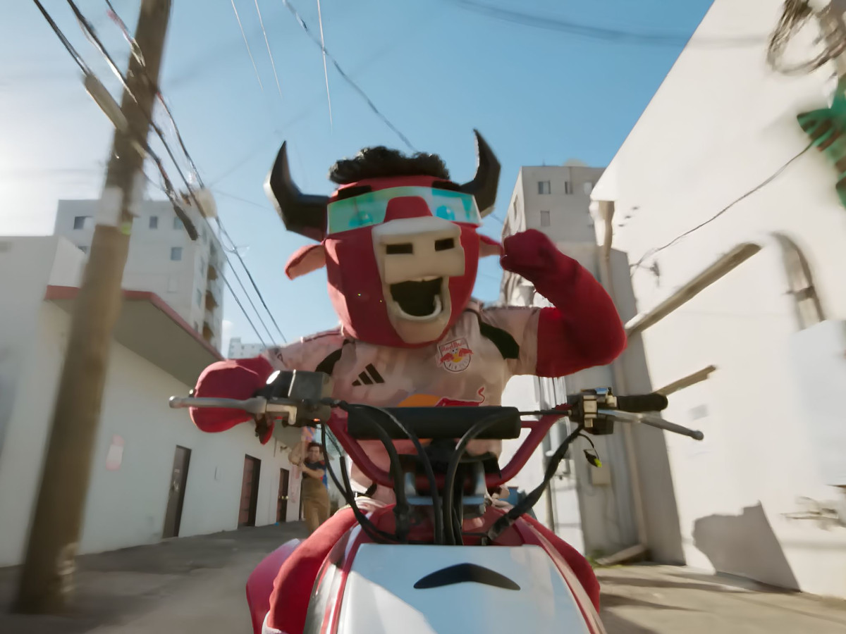 Bull mascot riding a motorcycle down an alley.