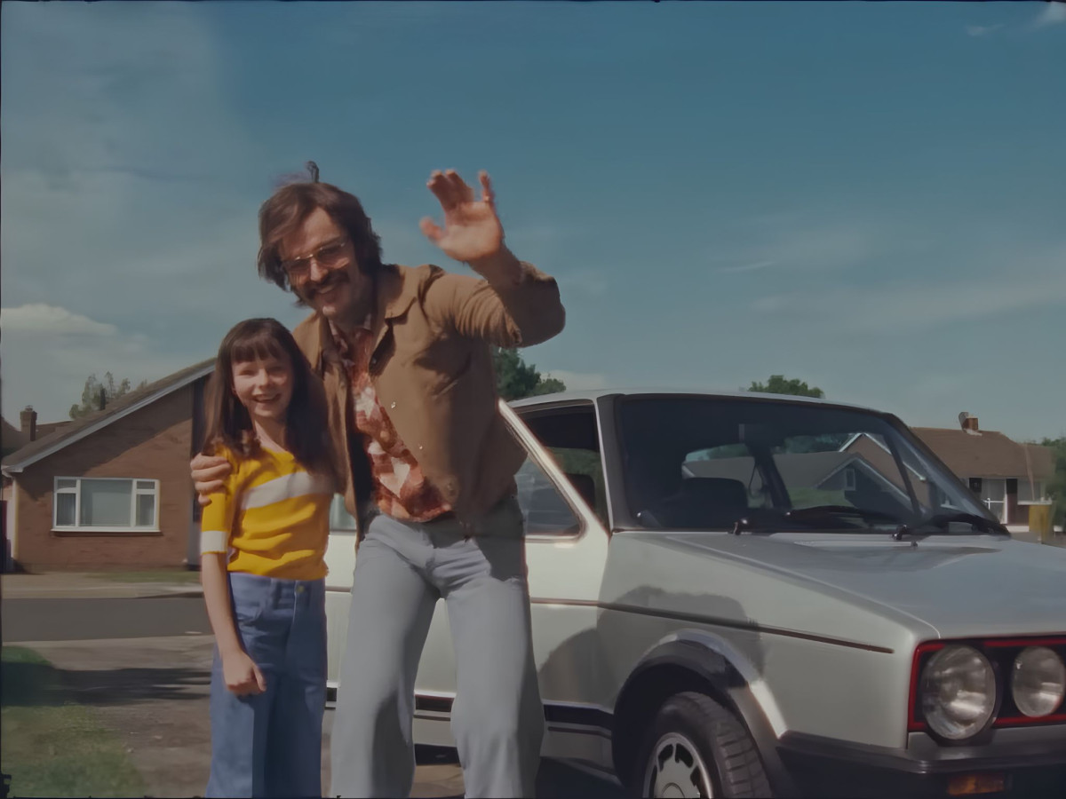 Man and girl waving by a vintage VW.
