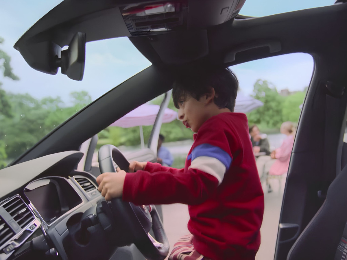 Boy pretending to drive a modern Volkswagen.