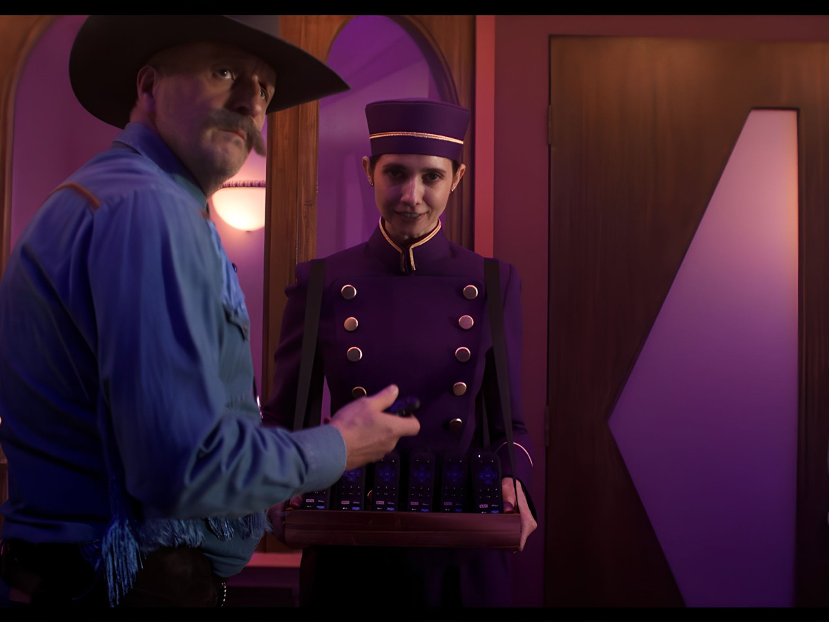 Cowboy beside a theater usher holding a tray of Roku remotes.