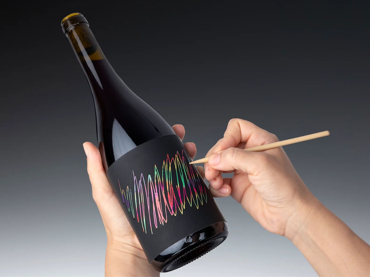 Scratching rainbow design on wine label.