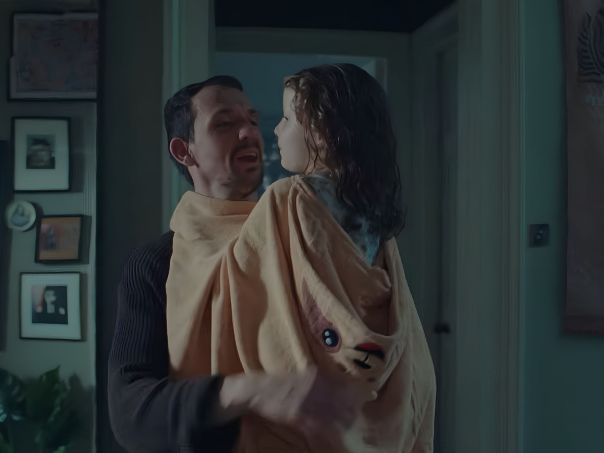 Man holding girl in a yellow towel.