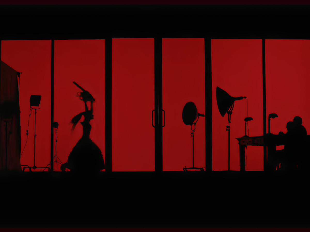 Silhouette of a woman carrying a chainsaw against a red background.