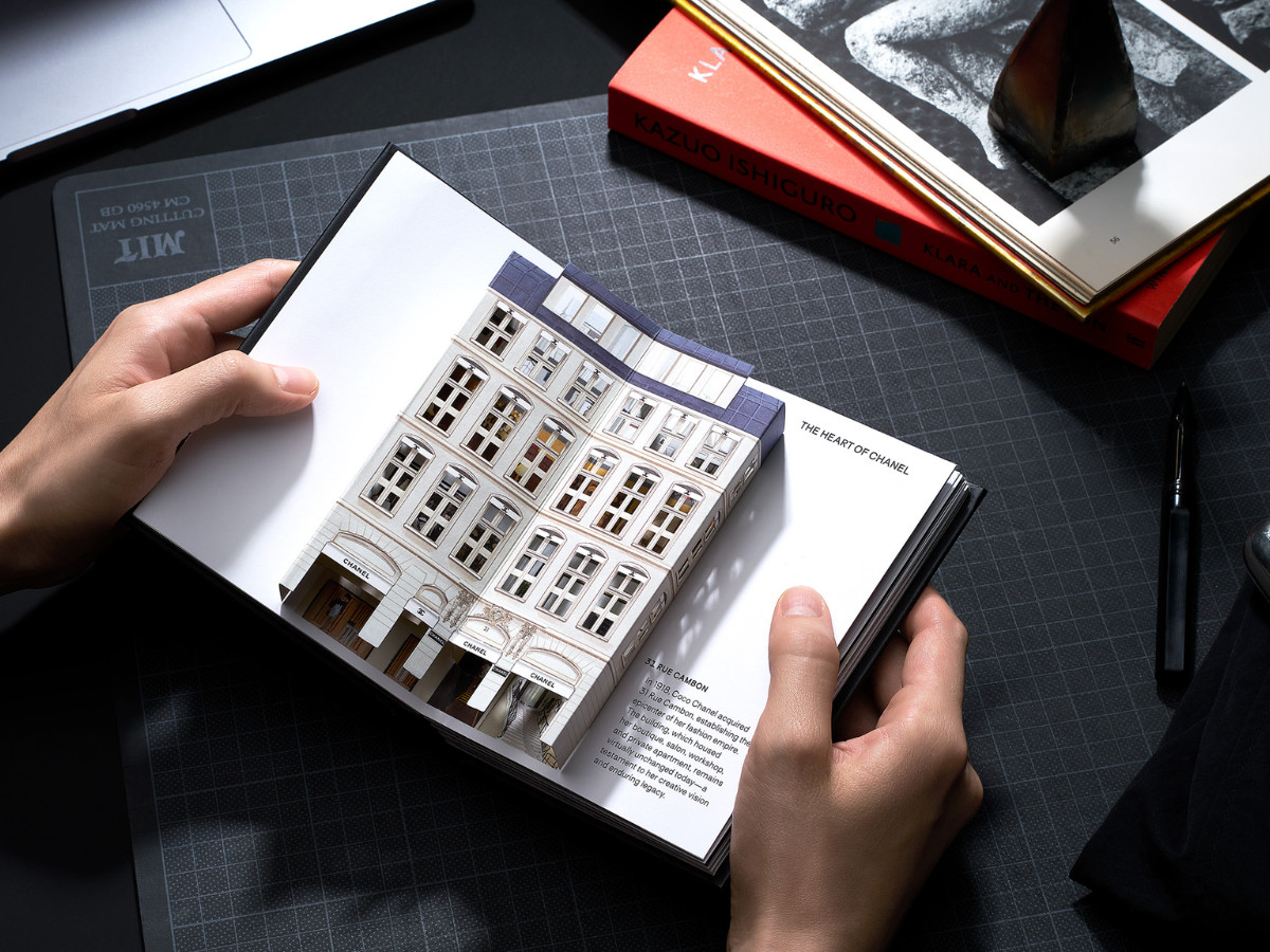 Hand holding a pop-up book displaying a 3D rendition of the Chanel headquarters in Rue Cambon