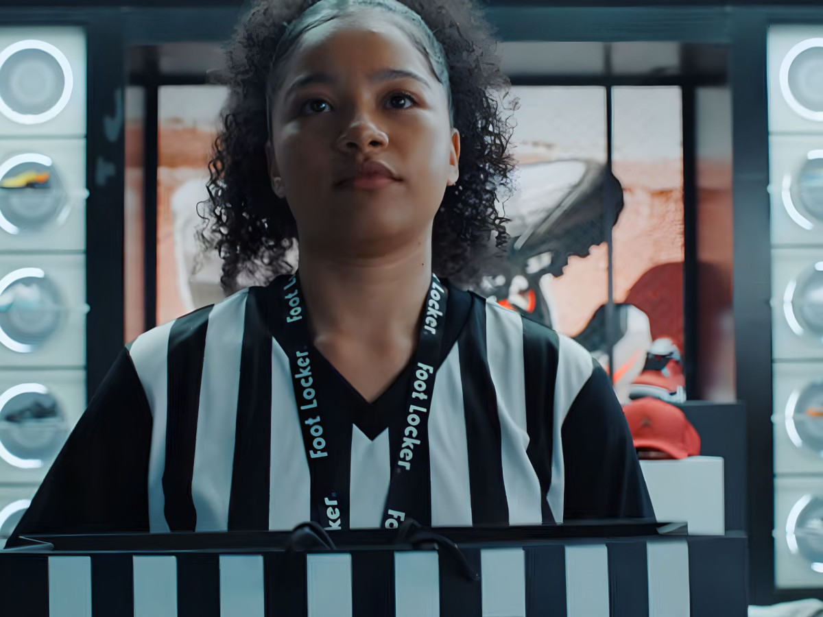 Foot Locker employee in a striped uniform holding a bag.