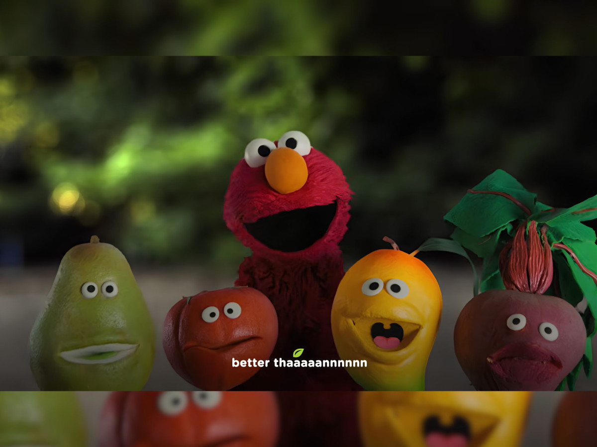 Elmo surrounded by singing fruits and vegetables.