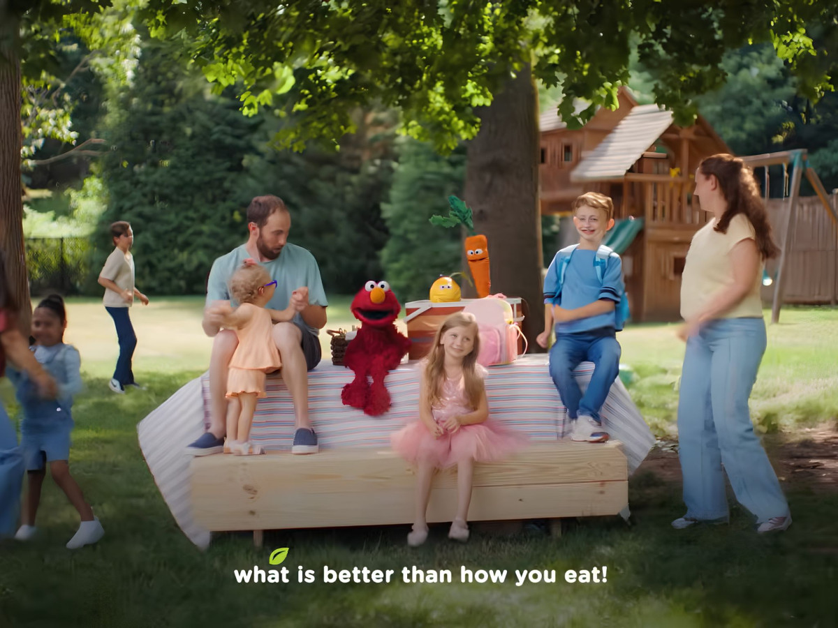 Elmo and a family enjoying an outdoor picnic.
